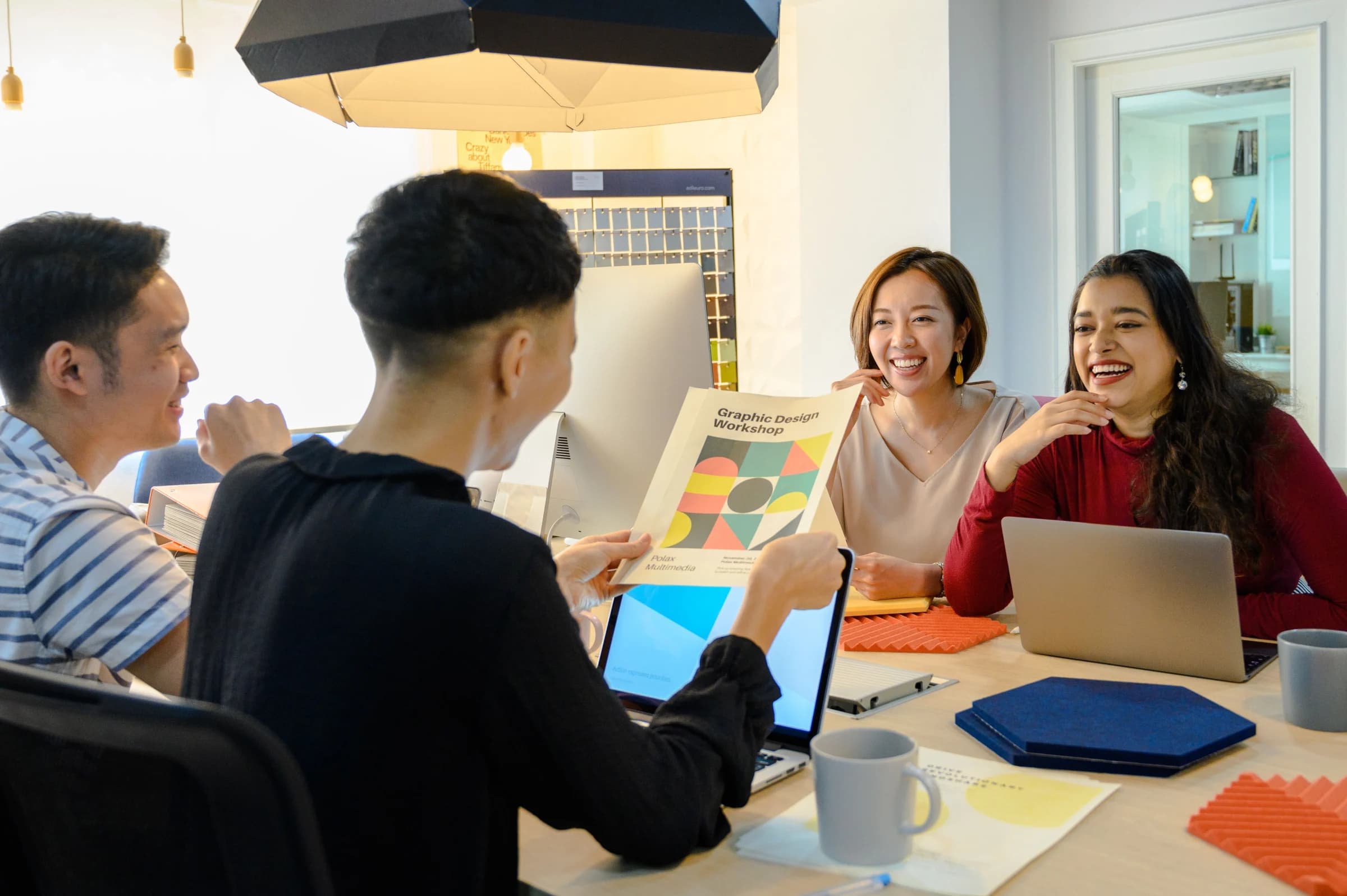 A small creative team laughing together around their work